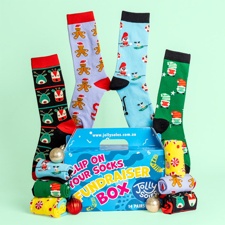Colorful socks with Christmas designs in a Jolly Soles Fundraiser Sock Box on a light green background