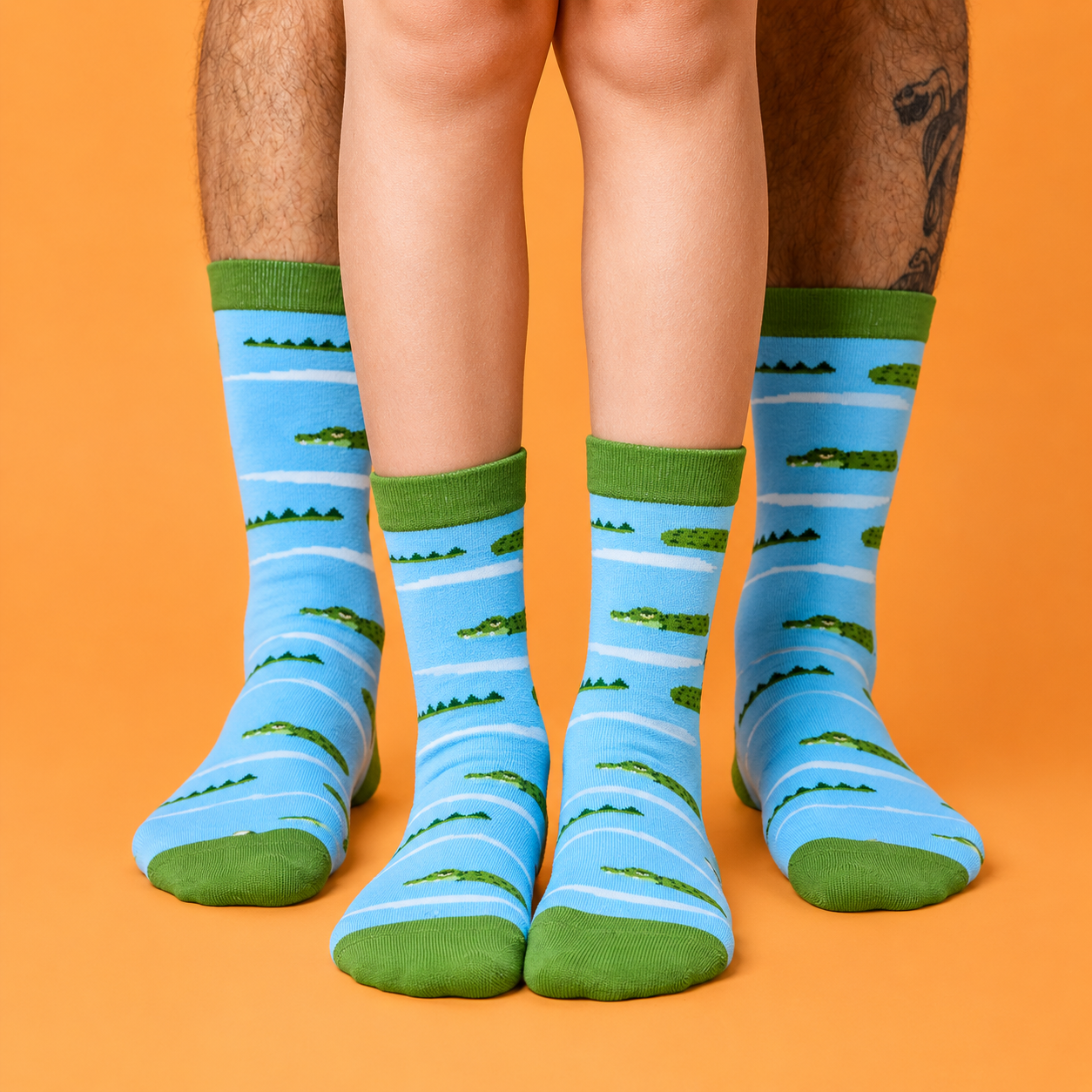 Blue Socks with a green heel, toe & logo featuring crocodiles, child and man wearing these socks matching.