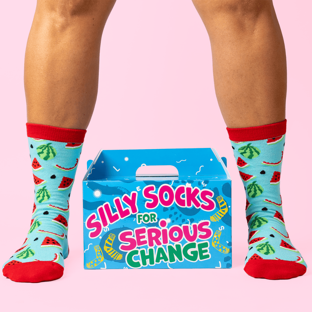 Person wearing watermelon socks with a 'Silly Socks for Serious Change' box on a pink background